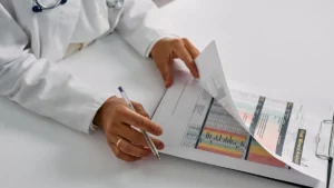 Bureau professionnel avec documents médicaux, stylo et lunettes de lecture dans une ambiance calme et éclairée naturellement.